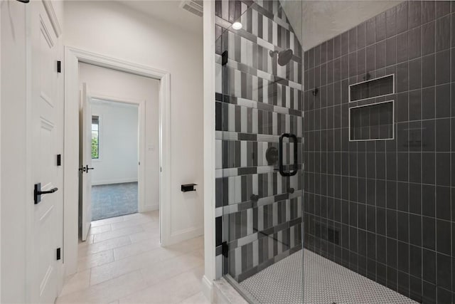 bathroom with tile patterned floors, tiled shower, and baseboards