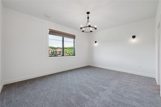 spare room with a notable chandelier, baseboards, and carpet floors