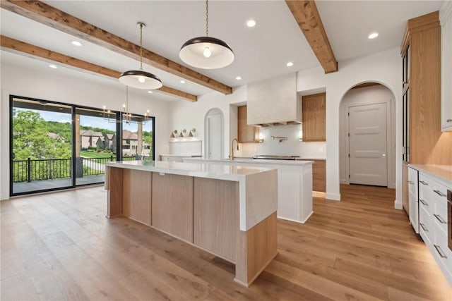 kitchen with light wood-style floors, a large island, light countertops, and custom range hood