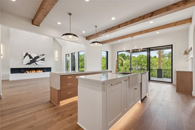 kitchen with a spacious island, a fireplace, light countertops, and light wood finished floors