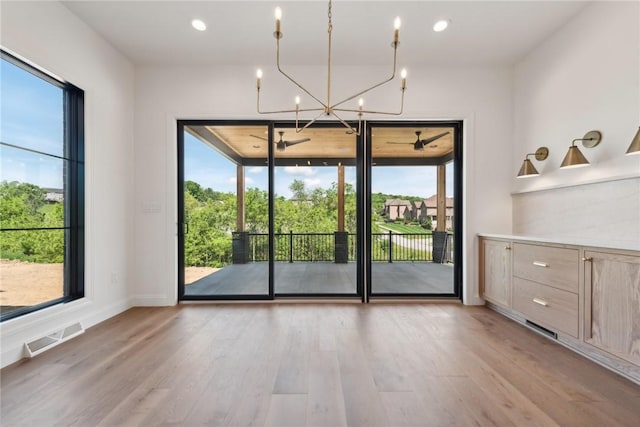 unfurnished dining area with baseboards, visible vents, light wood-style flooring, recessed lighting, and a chandelier