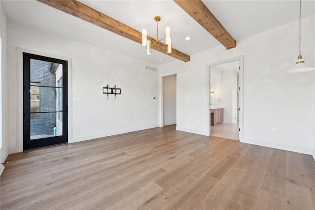 spare room featuring visible vents, beam ceiling, and light wood finished floors