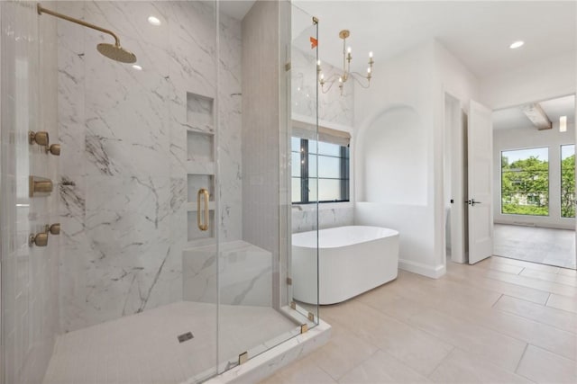 bathroom with a freestanding tub, a marble finish shower, a notable chandelier, and recessed lighting