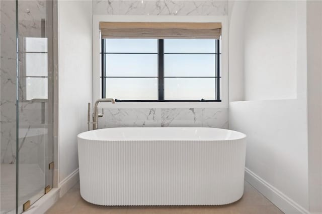 full bath featuring a marble finish shower, a soaking tub, tile patterned flooring, and baseboards