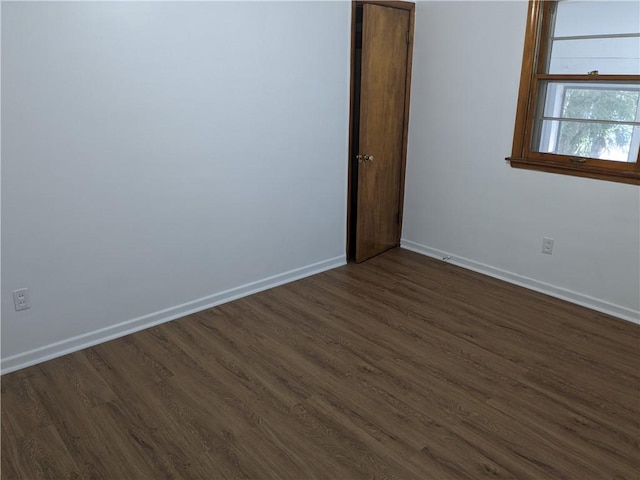 unfurnished room with baseboards and dark wood finished floors