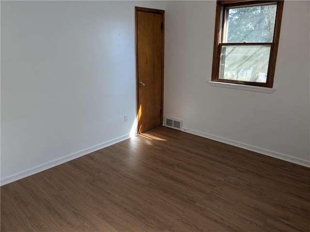 spare room featuring dark wood finished floors, baseboards, and visible vents