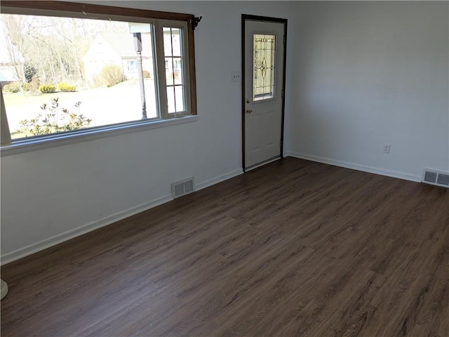 spare room with visible vents, baseboards, and dark wood-style flooring