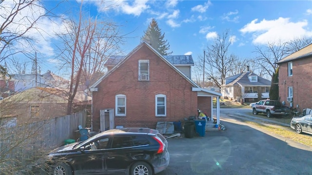 view of side of home with brick siding and fence