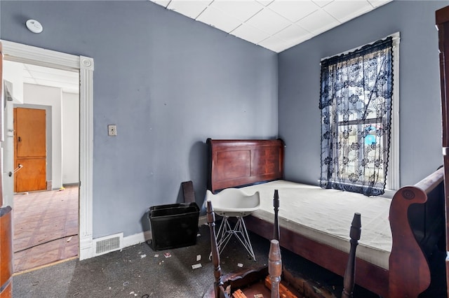 bedroom with baseboards, a paneled ceiling, and visible vents