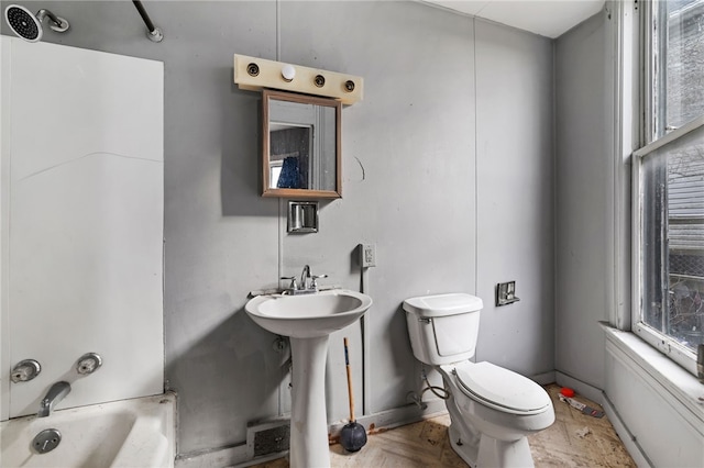 bathroom with a wealth of natural light, a bathing tub, toilet, and a sink