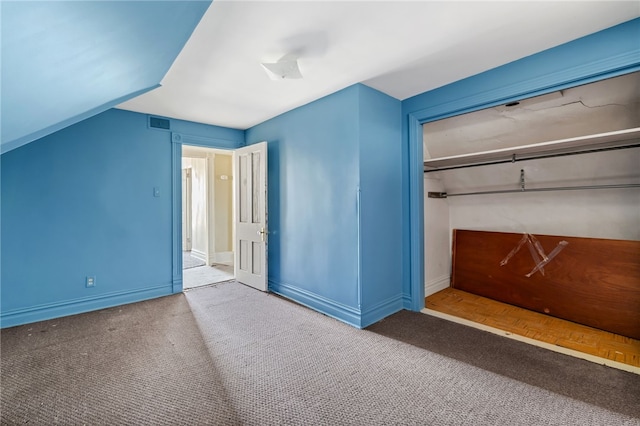 unfurnished bedroom featuring visible vents, baseboards, carpet, lofted ceiling, and a closet