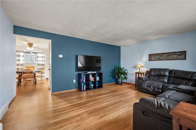 living room with ceiling fan, baseboards, and wood finished floors