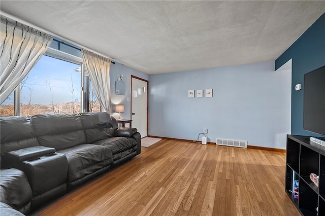 living area featuring visible vents, baseboards, and light wood-style floors