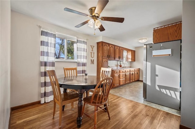 dining area with baseboards, light wood-style floors, and a ceiling fan