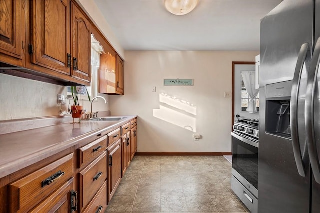 kitchen with wall oven, baseboards, stainless steel fridge with ice dispenser, brown cabinets, and a sink