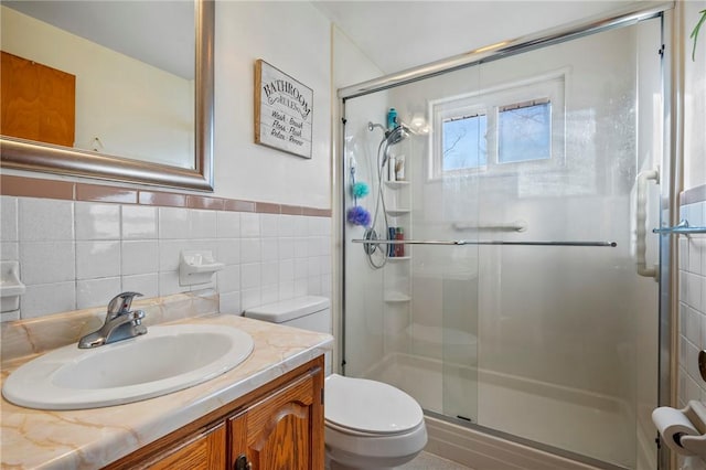 bathroom with vanity, tile walls, toilet, and a stall shower