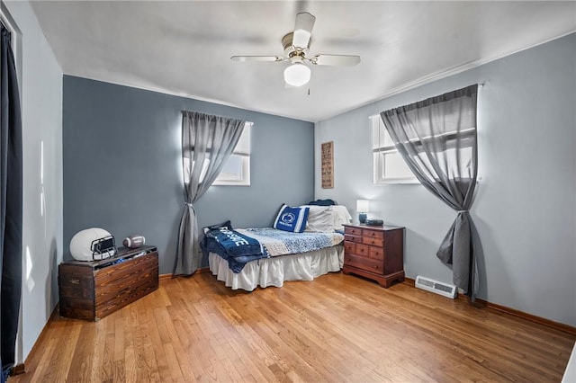 bedroom featuring a ceiling fan, baseboards, visible vents, and light wood finished floors