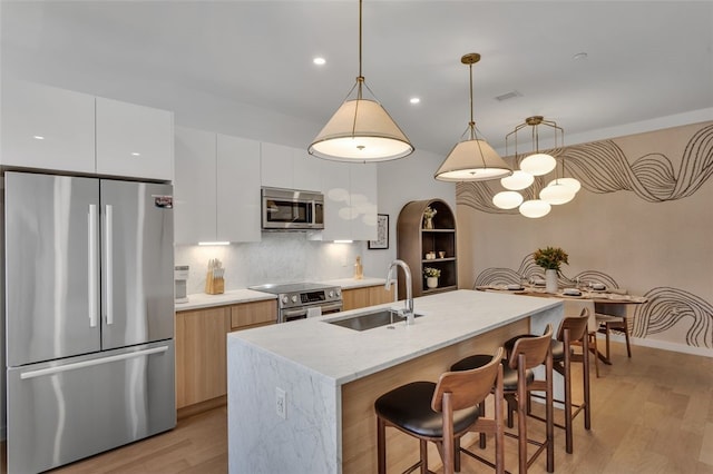 kitchen with a sink, stainless steel appliances, modern cabinets, and light wood-style flooring