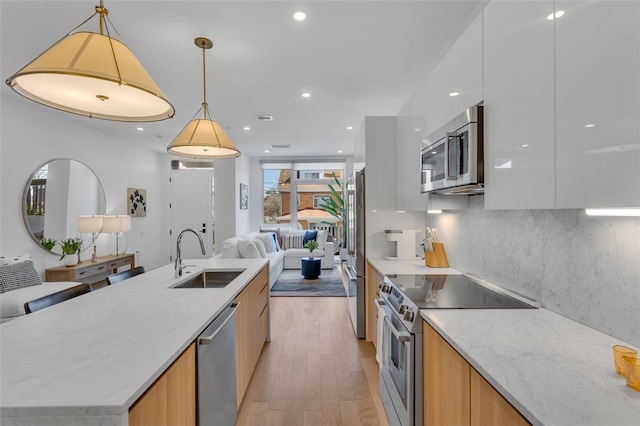 kitchen with a sink, modern cabinets, and appliances with stainless steel finishes