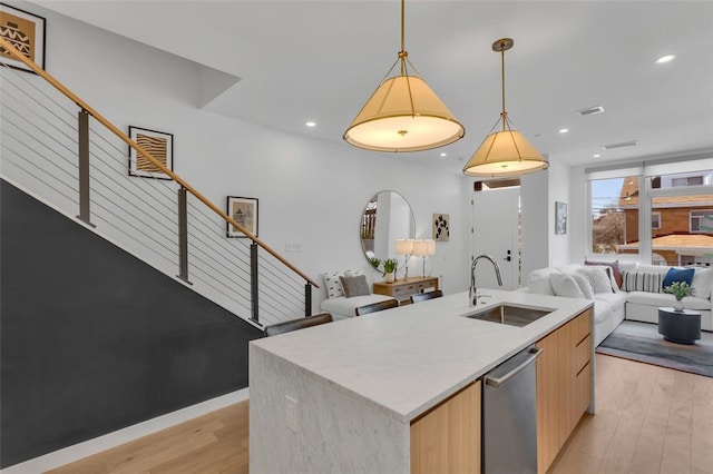 kitchen with a sink, open floor plan, stainless steel dishwasher, modern cabinets, and light wood-type flooring