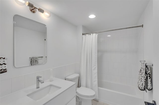 full bathroom featuring a wainscoted wall, shower / tub combo, toilet, and vanity