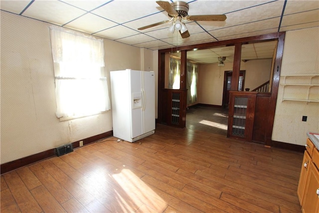 unfurnished room featuring a paneled ceiling, wood-type flooring, baseboards, and a ceiling fan