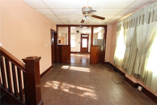 corridor featuring a drop ceiling and baseboards