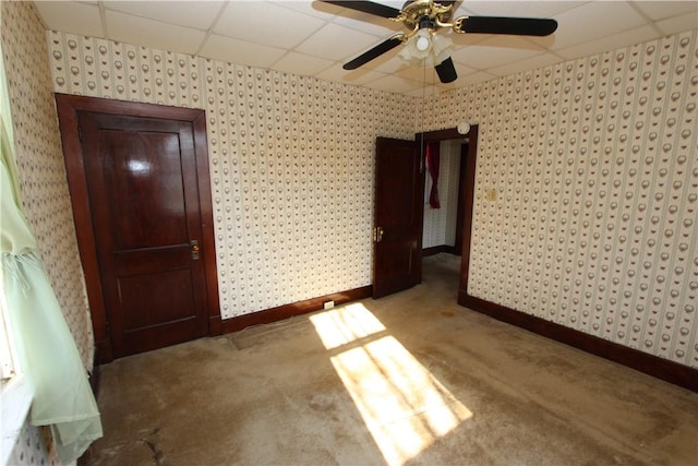 unfurnished bedroom with a drop ceiling, wallpapered walls, and carpet floors