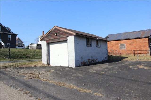 detached garage featuring driveway and fence