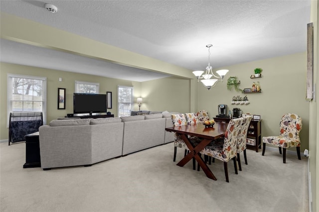 dining room featuring a textured ceiling, baseboards, a chandelier, and light carpet