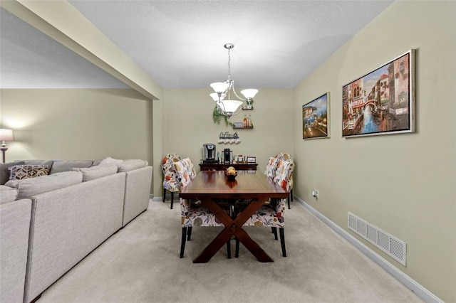 dining room featuring visible vents, baseboards, light colored carpet, and a notable chandelier