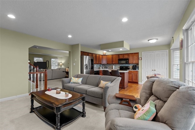 living room with recessed lighting, baseboards, a healthy amount of sunlight, and stairs