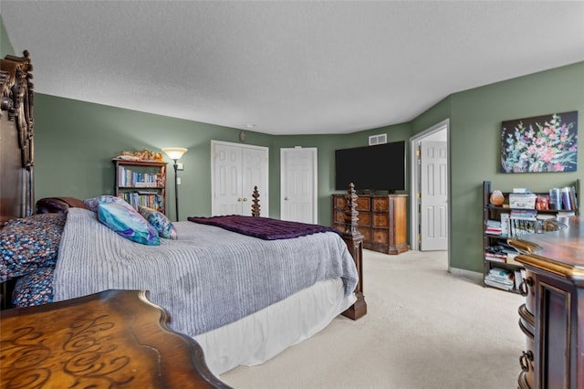 carpeted bedroom with visible vents, a textured ceiling, two closets, and baseboards