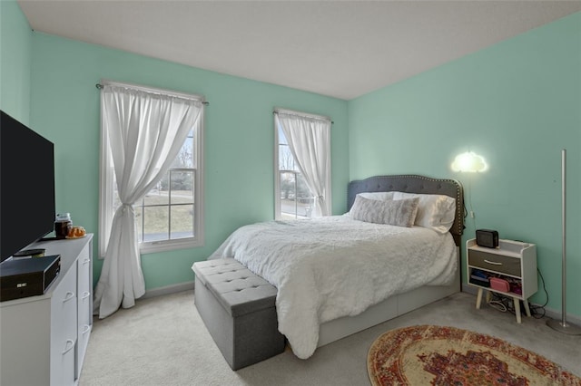 bedroom featuring multiple windows, baseboards, and light carpet