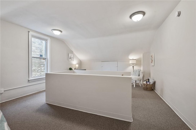 interior space with baseboards, lofted ceiling, and dark colored carpet