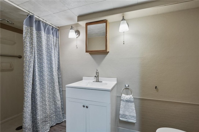 bathroom with wood finished floors, curtained shower, vanity, and a textured wall