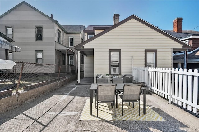 rear view of property featuring a patio, a fenced backyard, and a chimney