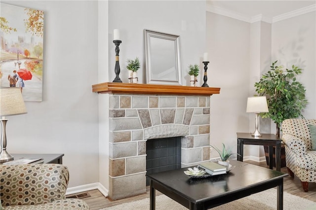 living area featuring visible vents, wood finished floors, a fireplace, crown molding, and baseboards