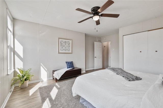 bedroom featuring ceiling fan, a closet, baseboards, and wood finished floors