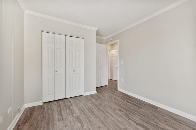 unfurnished bedroom featuring a closet, ornamental molding, baseboards, and wood finished floors