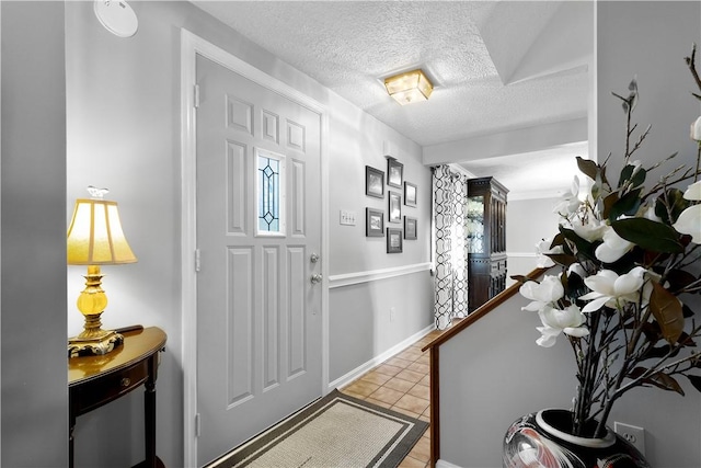 foyer with light tile patterned floors, baseboards, and a textured ceiling