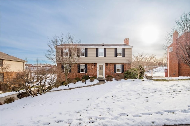 colonial house featuring brick siding and a chimney