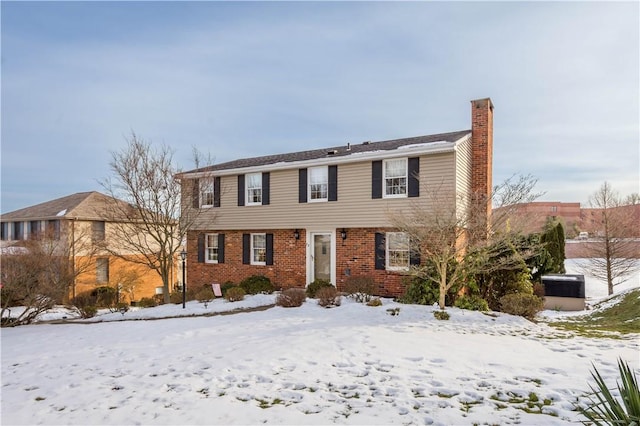 colonial home featuring brick siding and a chimney