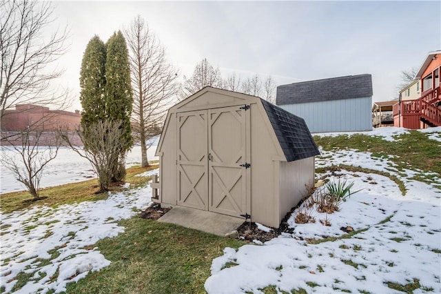 snow covered structure featuring a storage shed and an outdoor structure