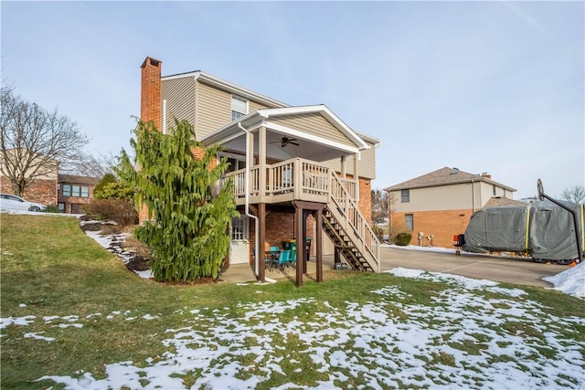 rear view of property featuring a yard, a chimney, stairs, ceiling fan, and brick siding