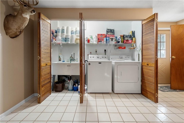 clothes washing area featuring baseboards, light tile patterned flooring, laundry area, and washer and clothes dryer