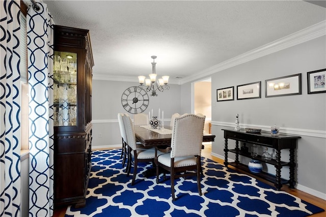 dining space featuring crown molding, baseboards, an inviting chandelier, wood finished floors, and a textured ceiling