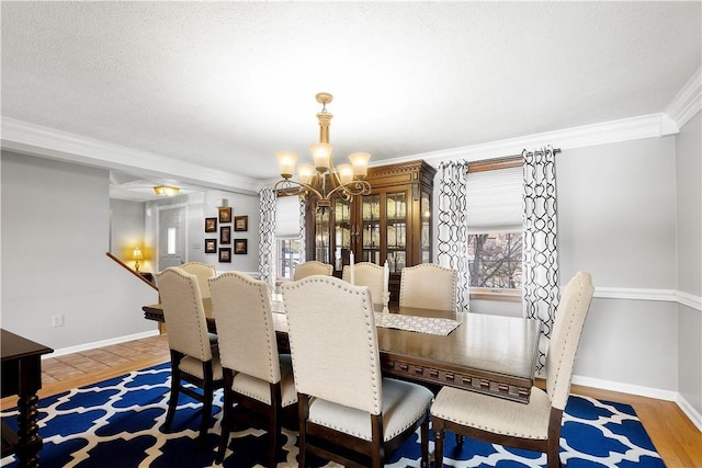 dining space featuring ornamental molding, a textured ceiling, wood finished floors, baseboards, and a chandelier