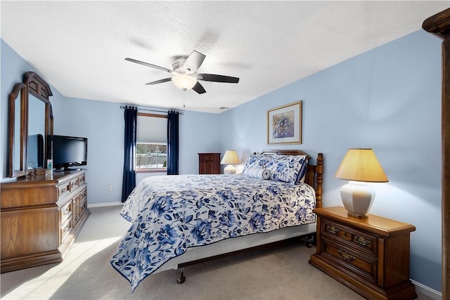 bedroom with light carpet, baseboards, a textured ceiling, and ceiling fan