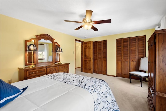 bedroom with baseboards, light carpet, a ceiling fan, and multiple closets